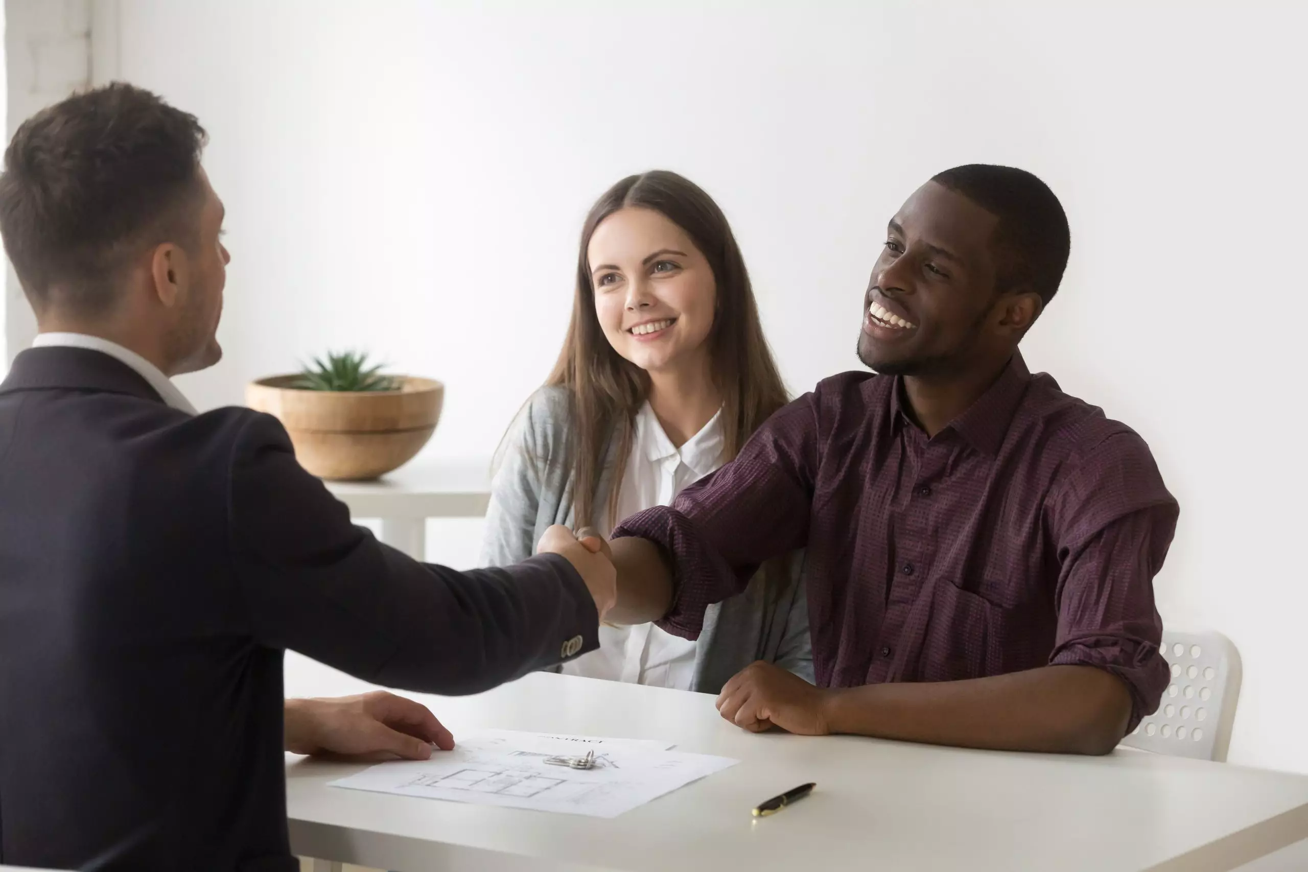 Happy satisfied interracial couple handshaking lender